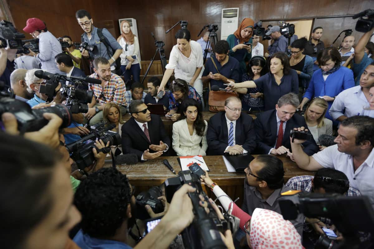 embers of the media surround Canadian Al-Jazeera English journalist Mohammed Fahmy, left, his lawyer Amal Clooney, center, Canadian ambassador to Egypt, Troy Lulashnyk, second right, before his verdict in a courtroom in Tora prison in Cairo (AAP)