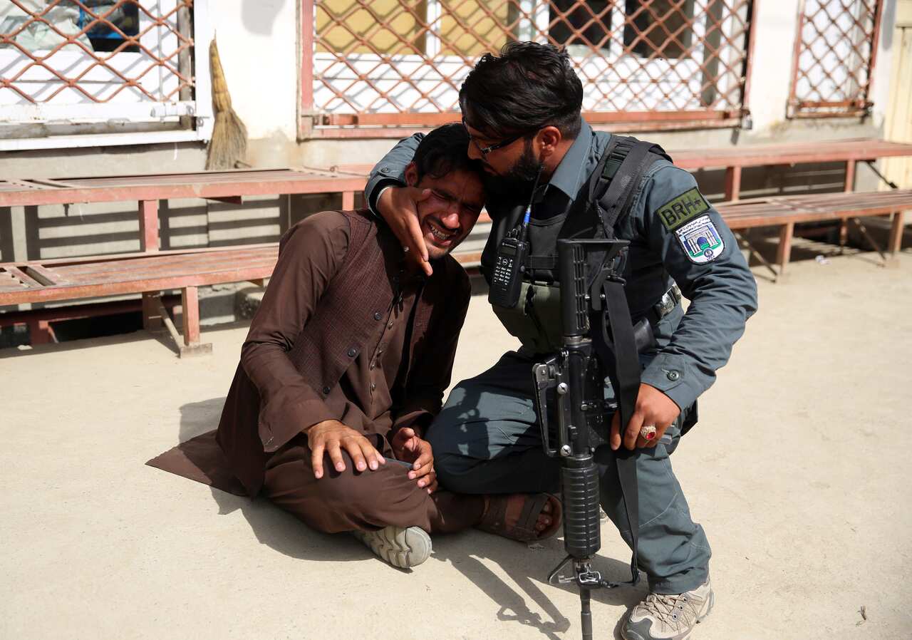 An Afghan policeman comforts a man (AAP)