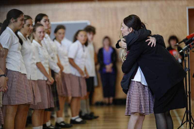 New Zealand's Prime Minister Jacinda Ardern, right, hugs and consoles a student during a high school visit in Christchurch.