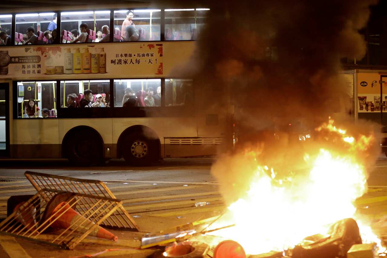 A double decker bus drives past burning debris during clashes between riot police and protesters in Hong Kong.