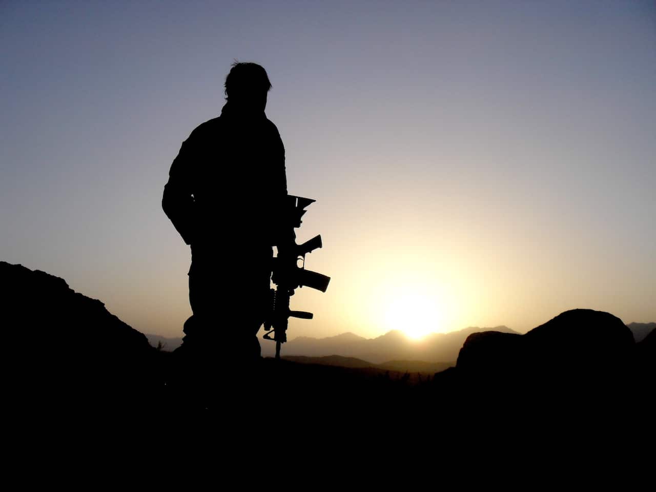 Silhouette of Australian soldier looking over mountains.