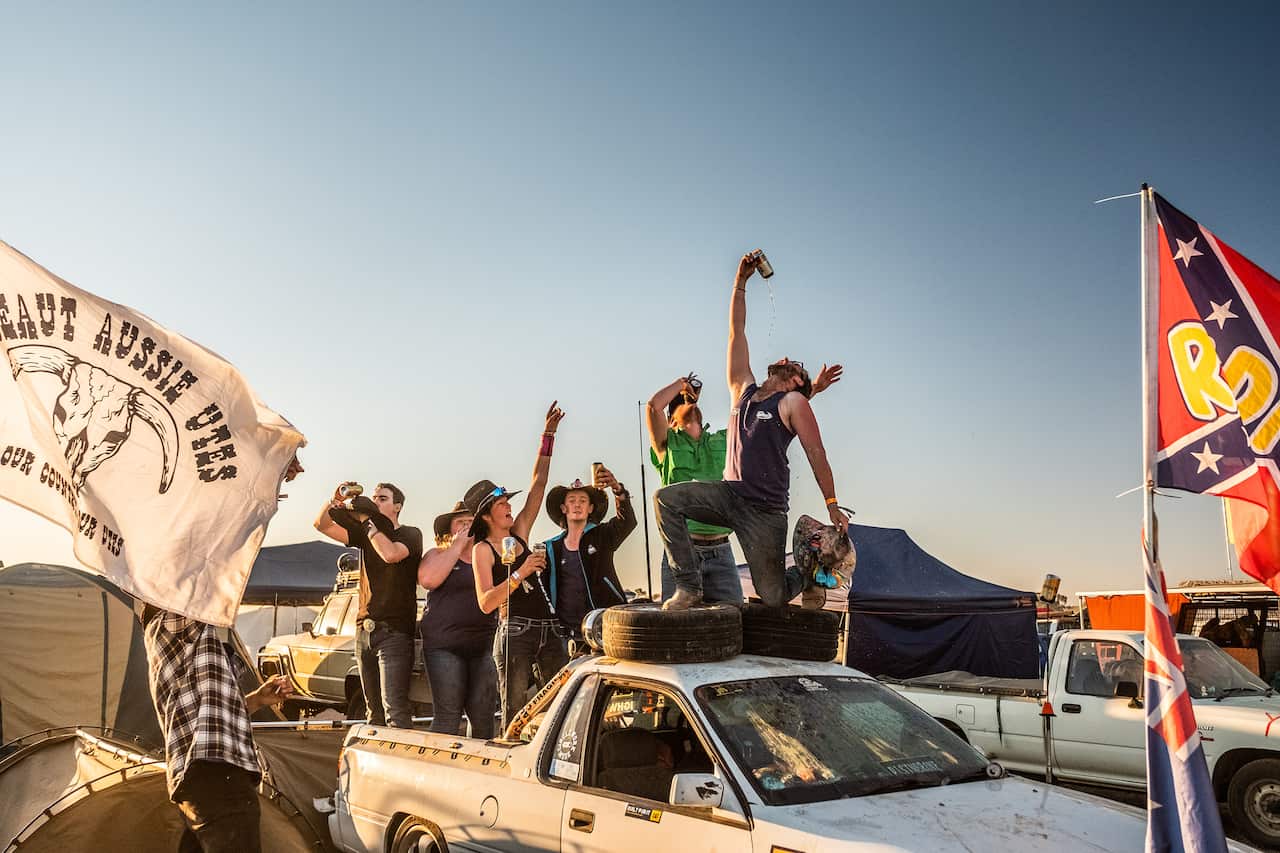 Rhys Martini pours a drink into his mouth as he stands atop a ute at the Deni Ute Muster.
