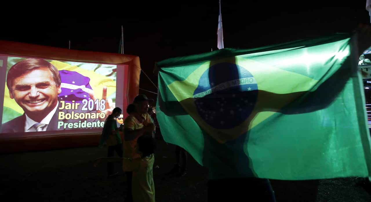 Supporters of presidential frontrunner Jair Bolsonaro of the Social Liberal Party, celebrate as they wait for the first results of the vote counting.