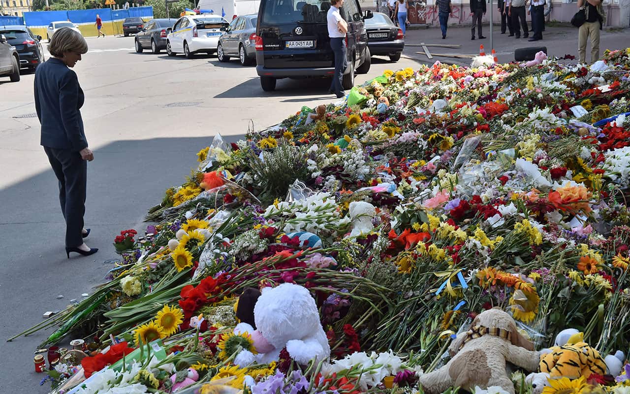 Julie Bishop walks past flowers laid in memory of victims of flight MH17 in front of the Netherlands' embassy in Kiev on July 2, 2014.