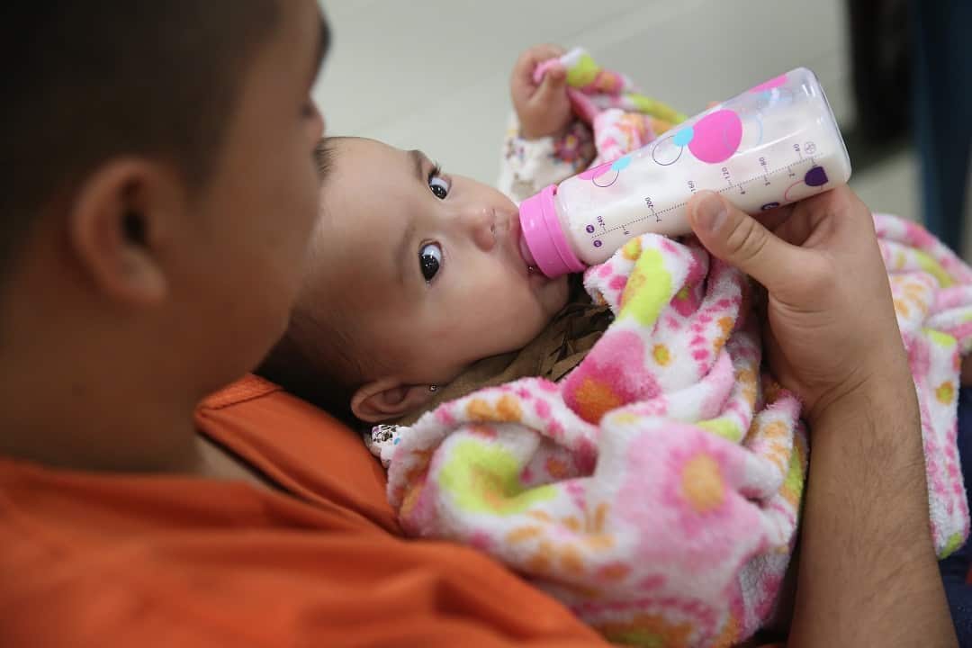 An immigrant detainee feeds his daughter during a family visitation visit at the Adelanto Detention Facility.