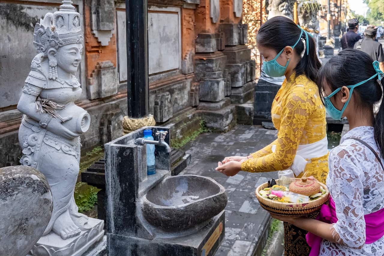 A Balinese woman washes her hands before entering a temple during Saraswati ceremony in Bali, Indonesia.