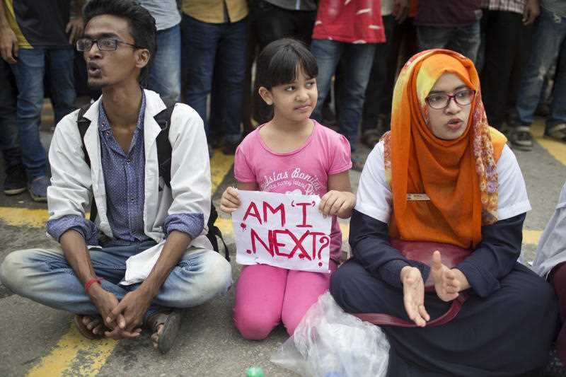 A Bangladeshi child holds a placard, as she sits with protesting students in Dhaka, Bangladesh.