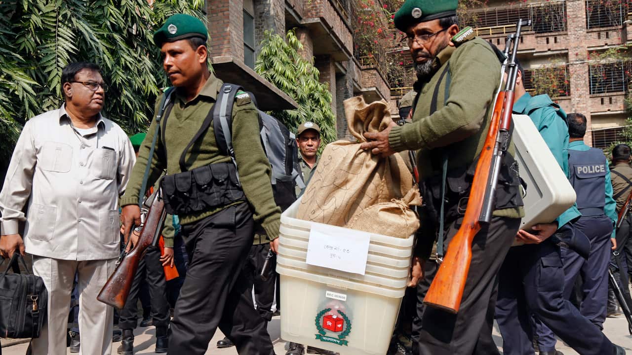 Election officials and Law enforcement member carry voting materials.