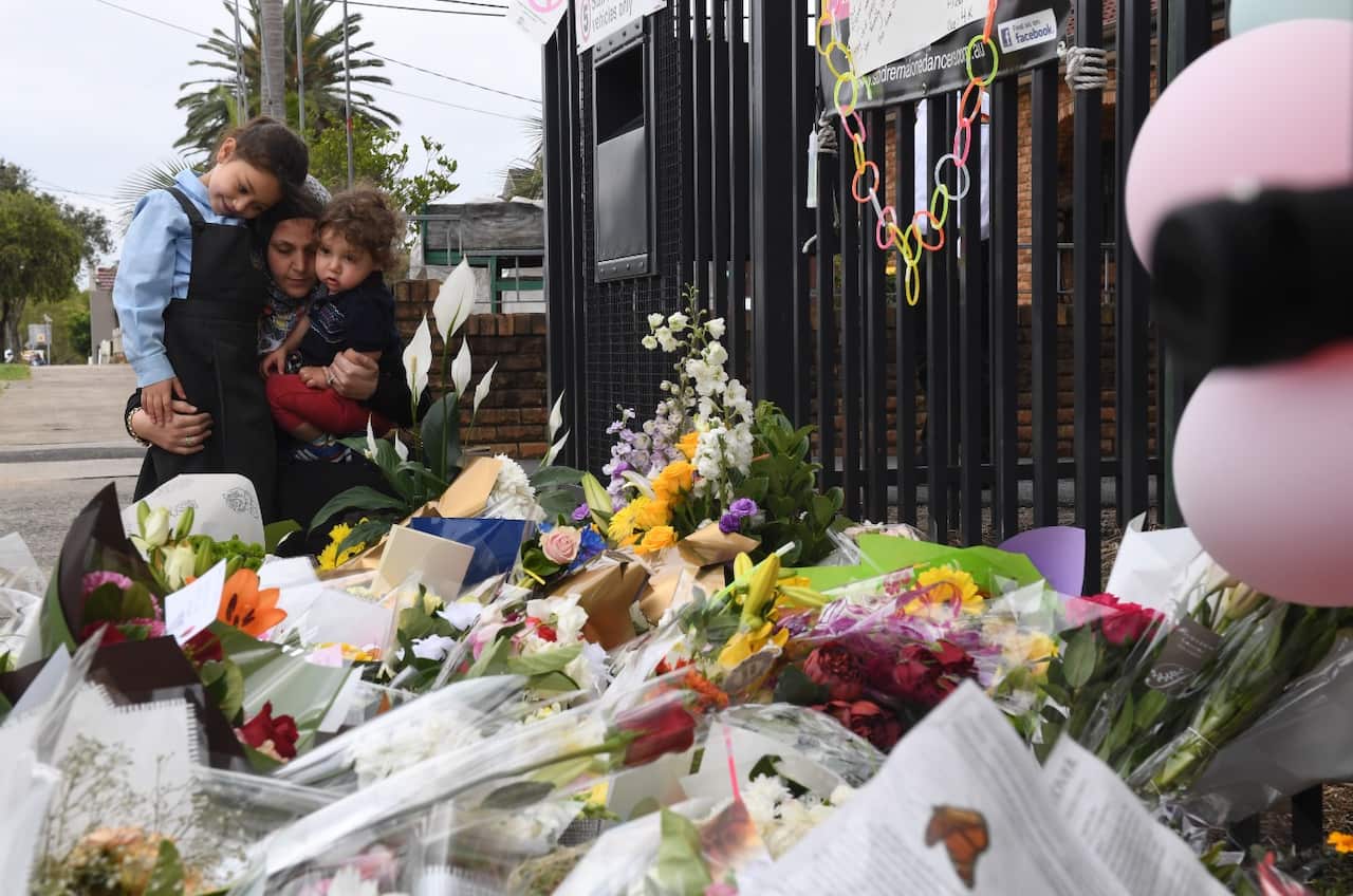 A mother and her young children place flowers outside the Banksia Road Public School in Greenacre, Sydney, Wednesday, November, 8, 2017.