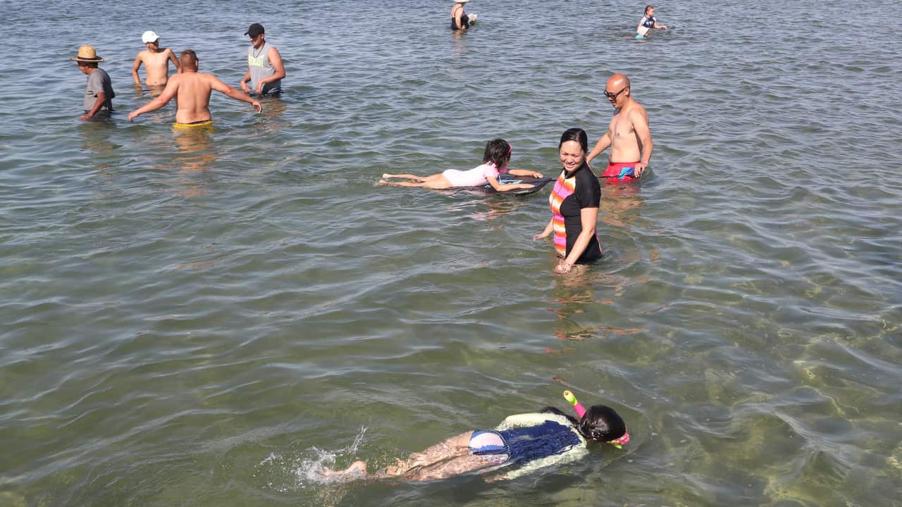 People are seen in the water at Altona beach in Melbourne on January 4 2019. 