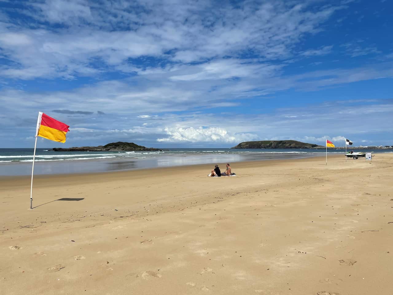 Two people sit on Park Beach near Coffs Harbour.