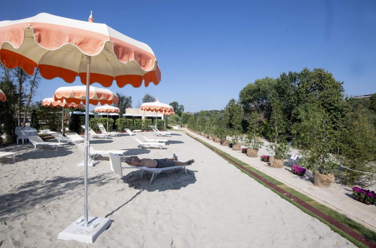 A man relaxes on a sunbed in the shadow of a parasol on the 'Tiberis' beach along the Tiber river, on its opening day, in Rome, Italy, 04 August 2018.