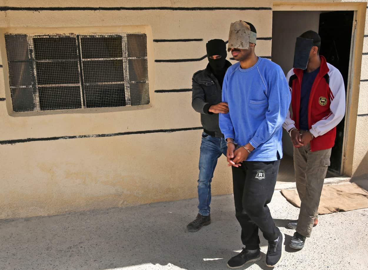 In this file photo dated Friday, March 30, 2018, a Kurdish security officer escorts Alexanda Kotey, left, and El Shafee Elsheikh.