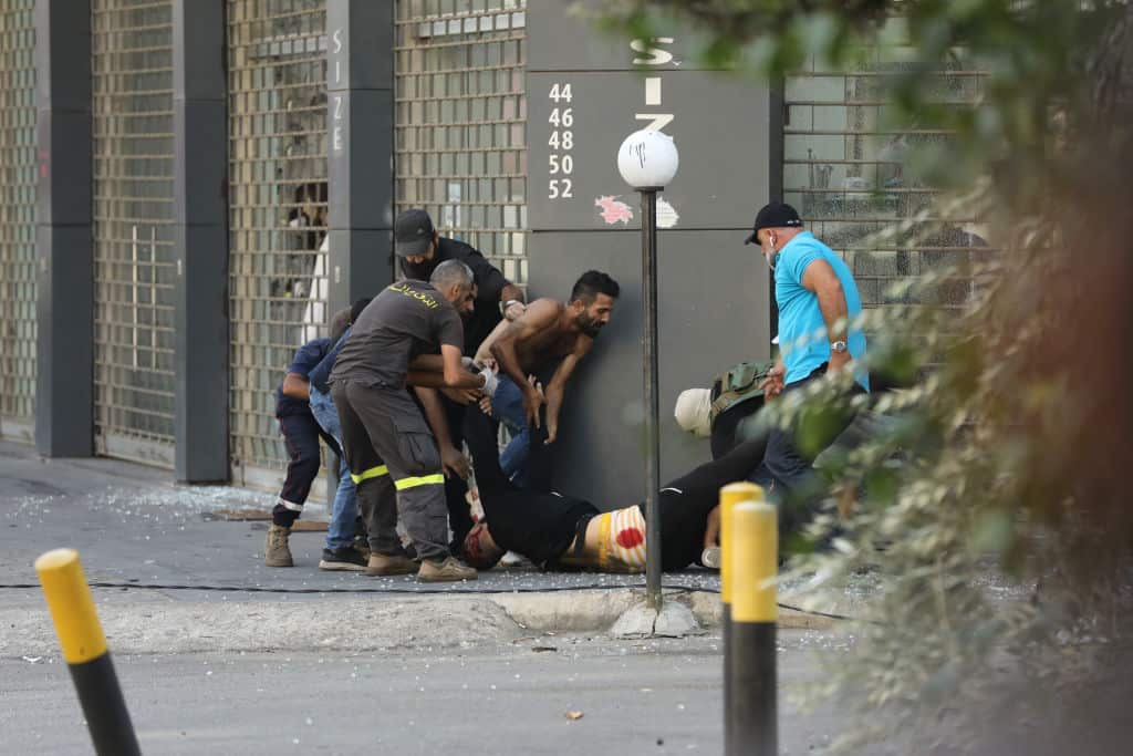 Civilians and emergency personnel rush an injured man to safety following deadly clashes in Beirut.