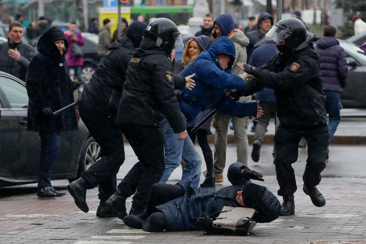 A woman is pushed to the ground by police