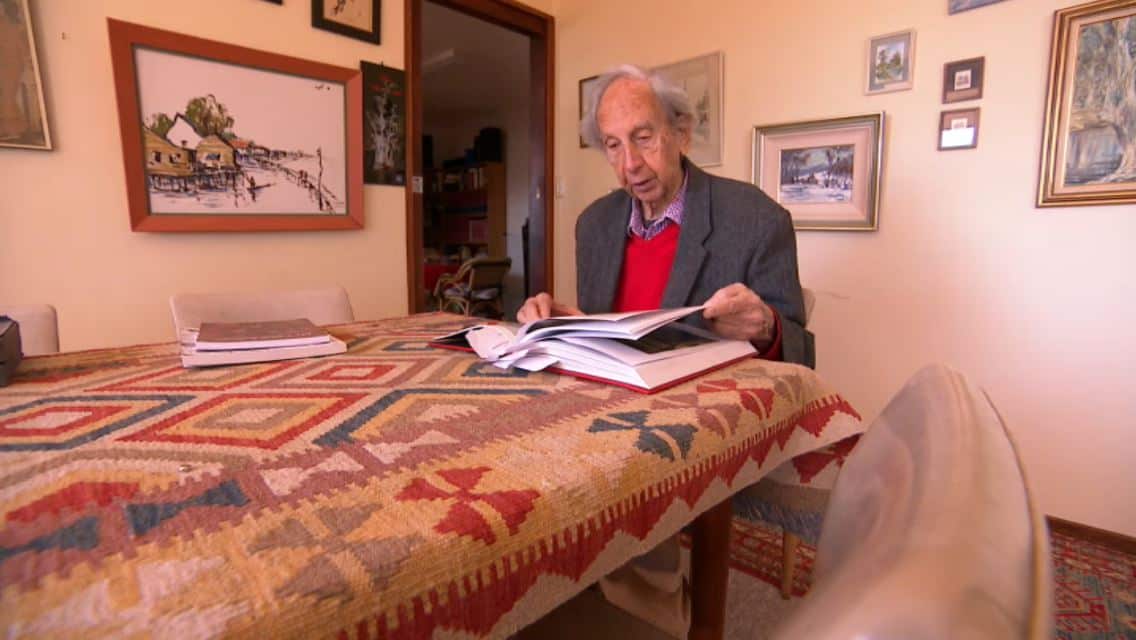 Bern Brent reading through Dunera history books in his home in Canberra.