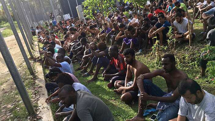 Asylum seekers sit on the ground as they refuse to leave the Manus Island detention center in Papua New Guinea