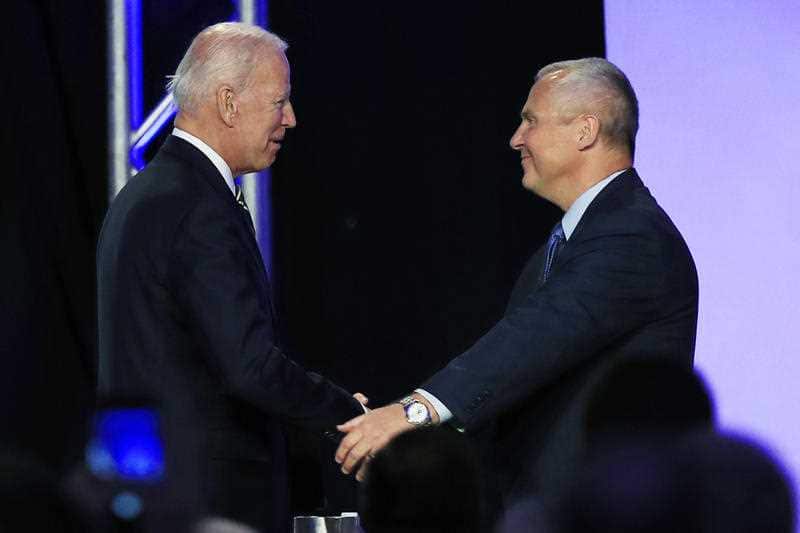 Biden is greeted by International Brotherhood of Electrical Workers President Lonnie Stephenson as he arrives to speak.