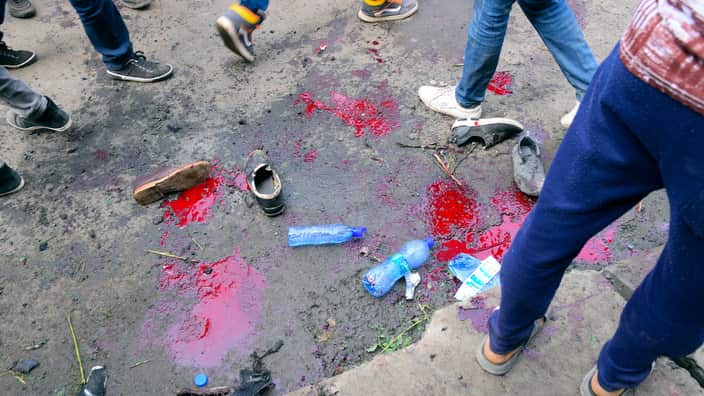 Pools of blood are seen on the ground as people gather at the scene of the explosion.