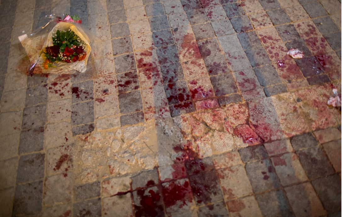 Flowers rest on a bloodstained area of ground after a stabbing attack. 