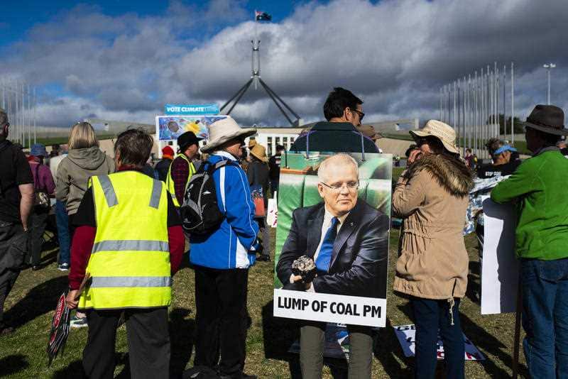 Protestors holding signage during the stop Adani Rally outside Parliament House in Canberra.