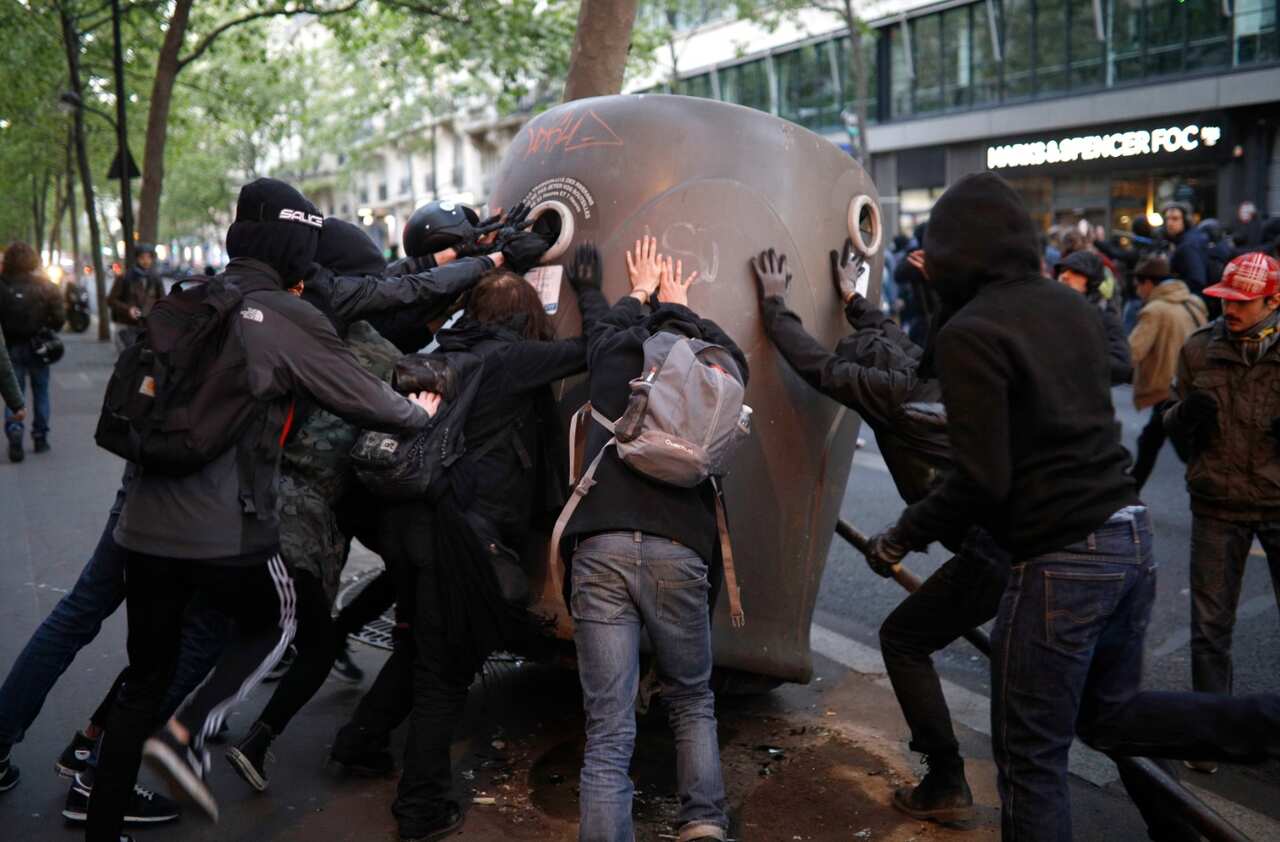  Youth push over a glass bottle container during in Paris , Sunday April 23, 2017. (AAP)