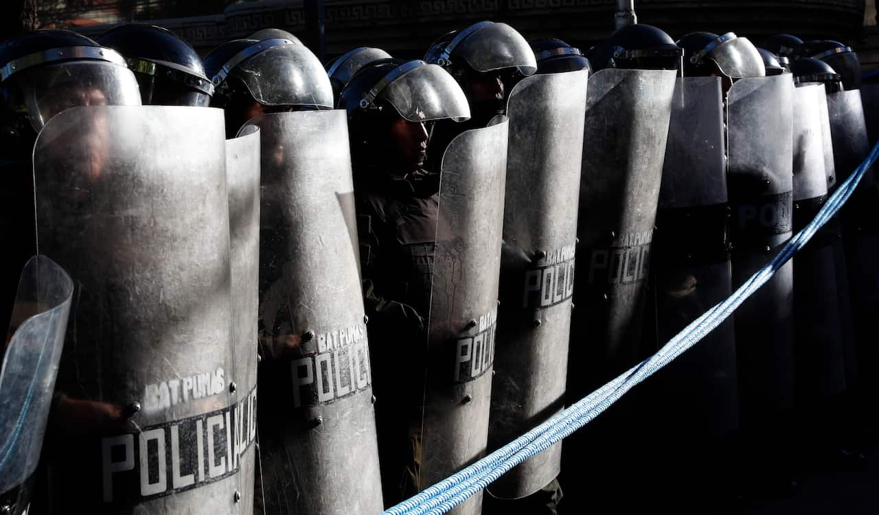 Police stand guard outside the  top electoral court as protesters approach. 
