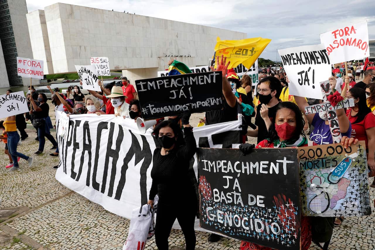 Demonstrators carry signs written in Portuguese calling for the impeachment of Jair Bolsonaro in Brasilia, Brazil on 17 January 2021.