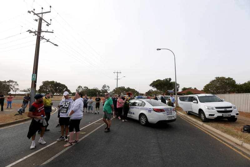 Locals gather outside the exclusion zone as police secure the area. 