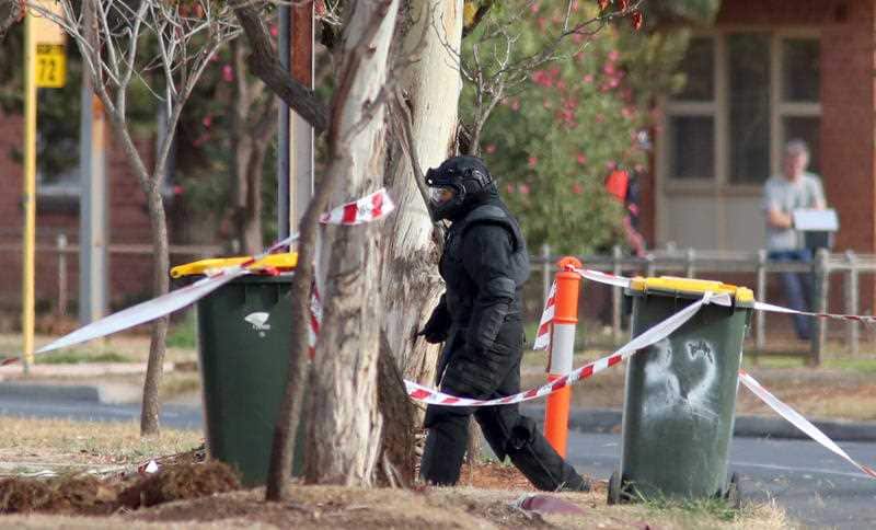 A Bomb Squad technician approaches the home.