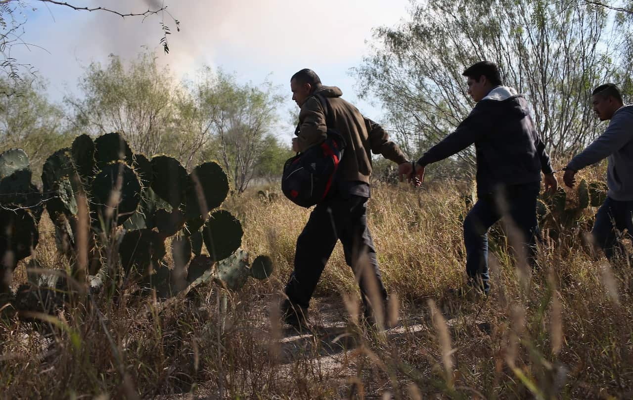 Immigrants walk handcuffed after illegally crossing the US-Mexico border and being caught by the US Border Patrol (Getty)