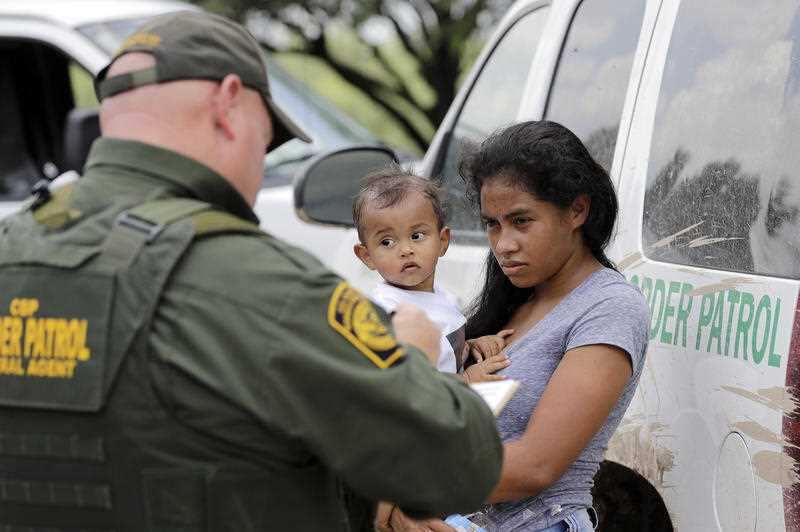 A mother migrating from Honduras holds her one-year-old child as surrendering to Border Patrol agents after illegally crossing the Texas border.