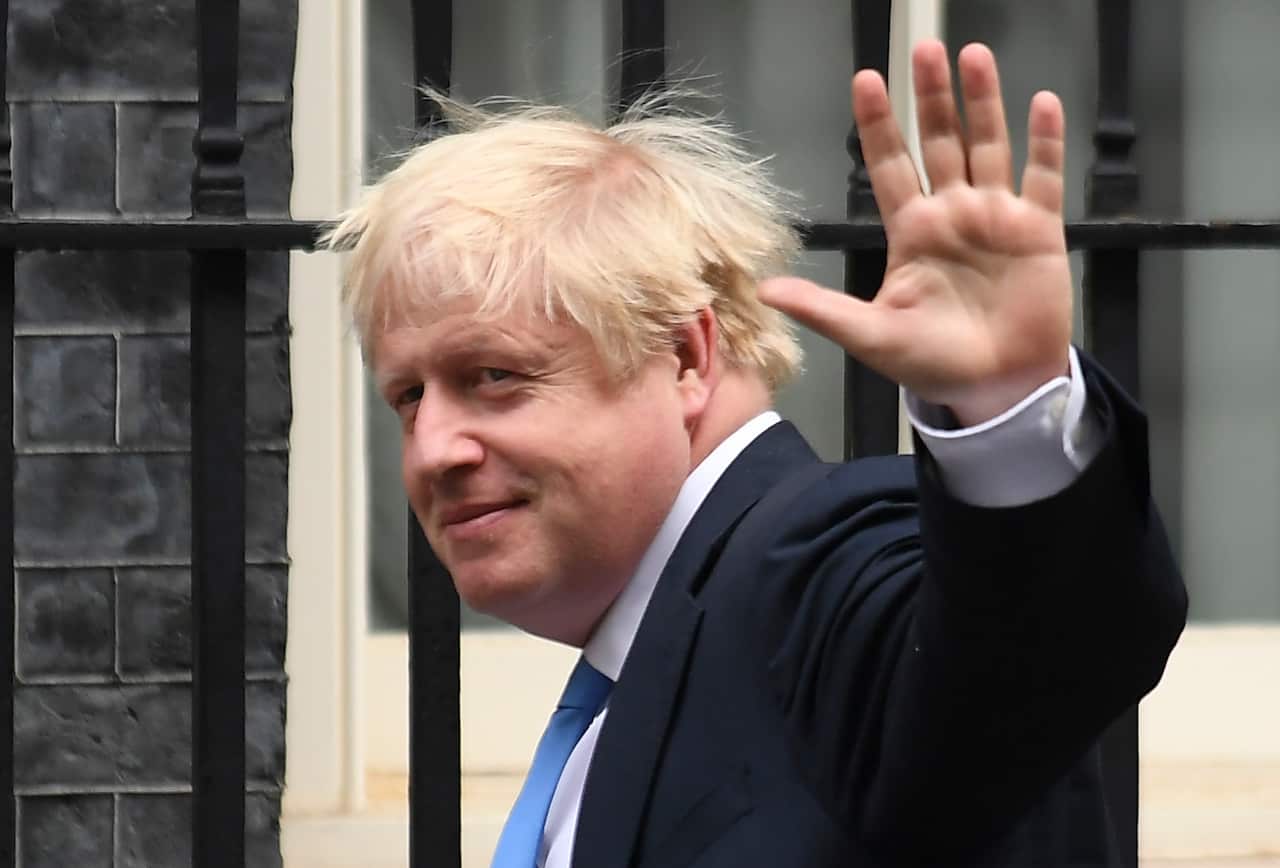 Mr Johnson waves at the media as he arrives at 10 Downing Street.