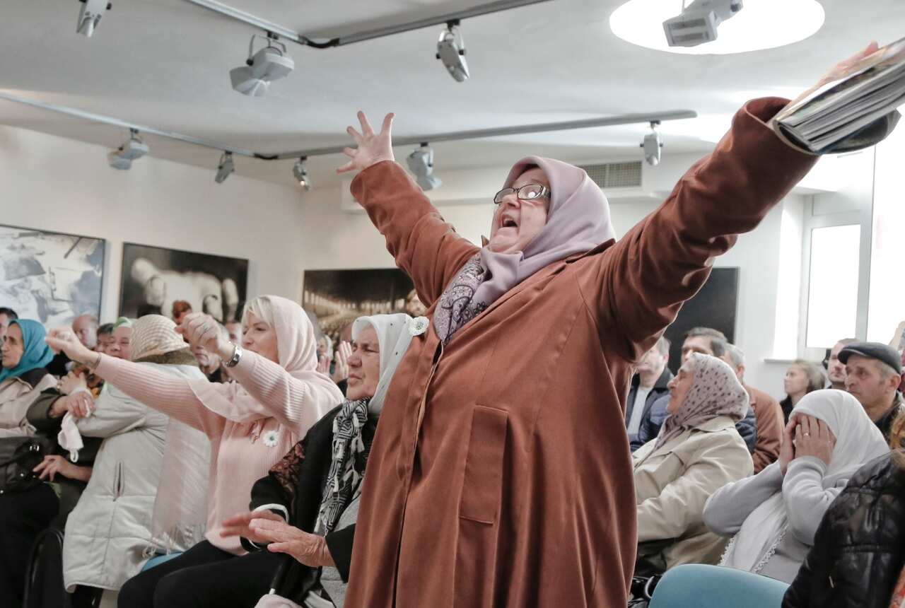 Ediba Salihovic, right, stands up and raises her hands as she reacts along with other Bosnian women upon hearing the sentence (AAP)