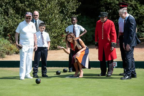 First Lady Melania Trump tries her hand at lawn bowls as Philip May, husband of UK Prime Minister Theresa May, watches during a visit to The Royal Hospital.