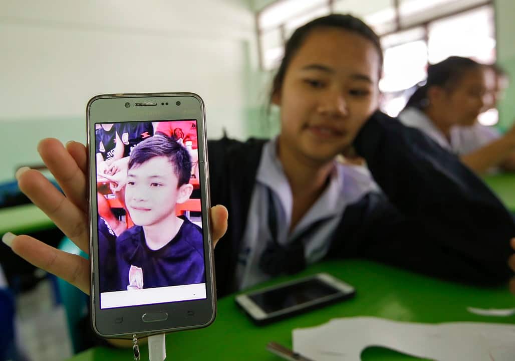 A student shows an image of her classmate Duangpetch Promthep, who is one of 13 members of the soccer team team trapped in Tham Luang cave.