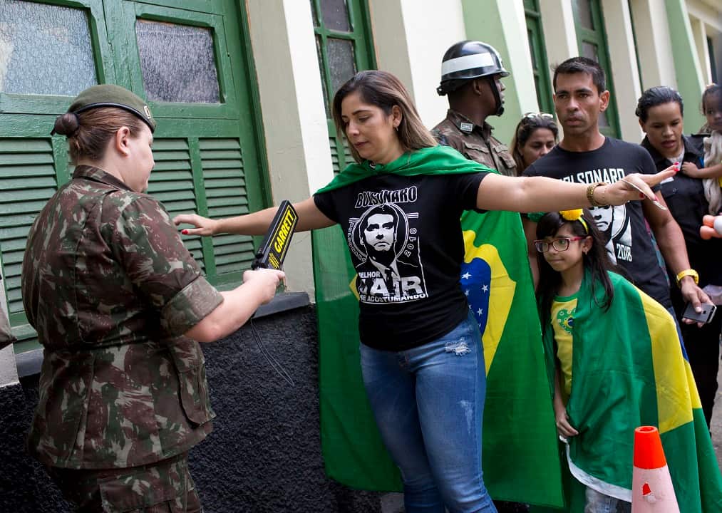 A Jair Bolsonaro supporter runs through a security at a polling station in Rio de Janeiro, Brazil.