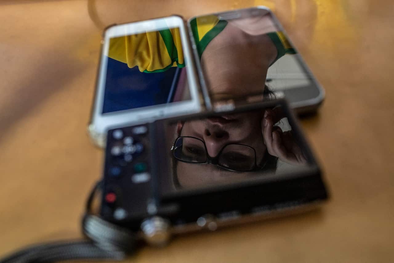 Reflected in devices, Matheus Dominguez, who said YouTube was crucial to shifting his political views to the far right, recording a YouTube video in Niteri, Brazil, April 29, 2019.  (Dado Galdieri/The New York Times)