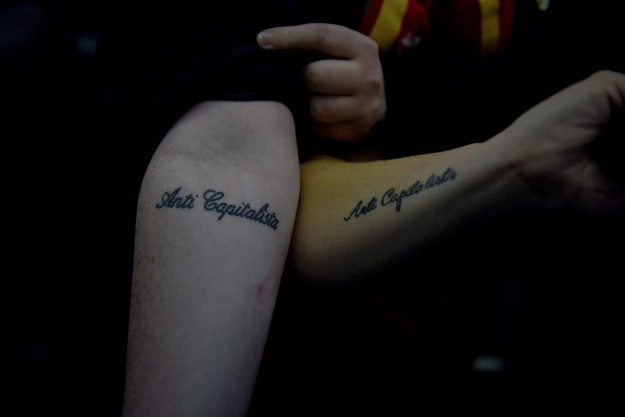 Lauren McCourt and Shen Batman show off their matching Anti Capitalista tattoos as they return home to Brighton, England, after attending a rally to demand fairer pay and better working conditions at Wetherspoons restaurants, in London.