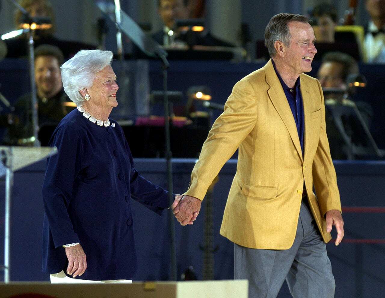 Former US President George H.W. Bush and former First Lady Barbara Bush smile as they are introduced at Bush's 80th birthday celebration in 2004.