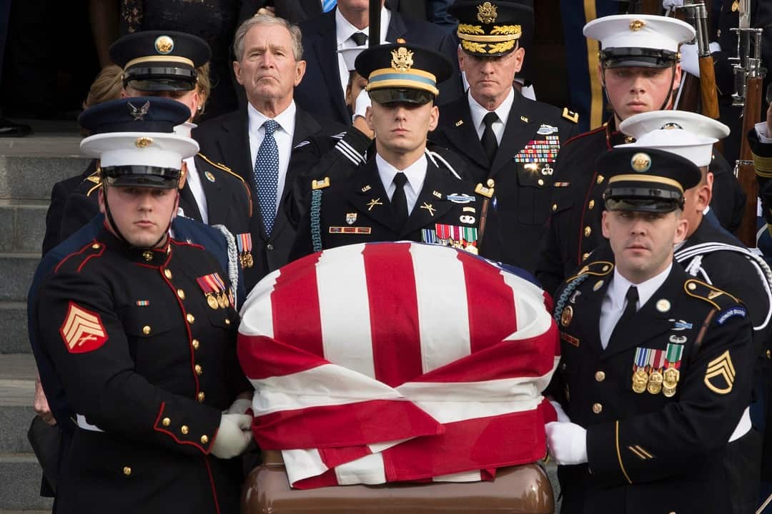Former US President George W Bush other Bush family members watch the casket bearing his father's remains being carried out of the funeral. 