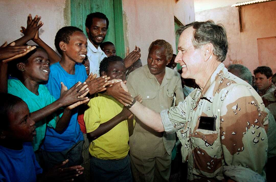 George HW Bush greets Somali children applauding him during a visit to an orphanage in famine-ravaged Baidoa in 1993. 