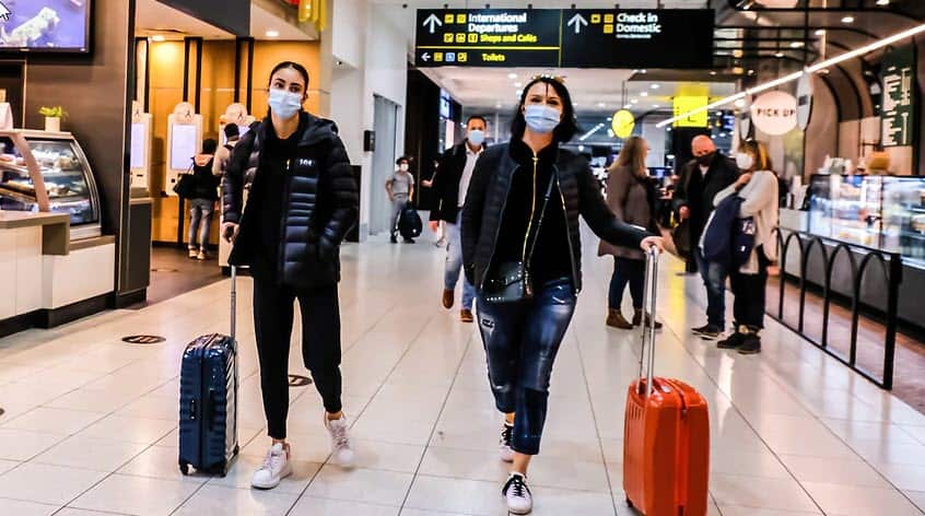 Passengers with suitcases walk through a food court at Melbourne airport.