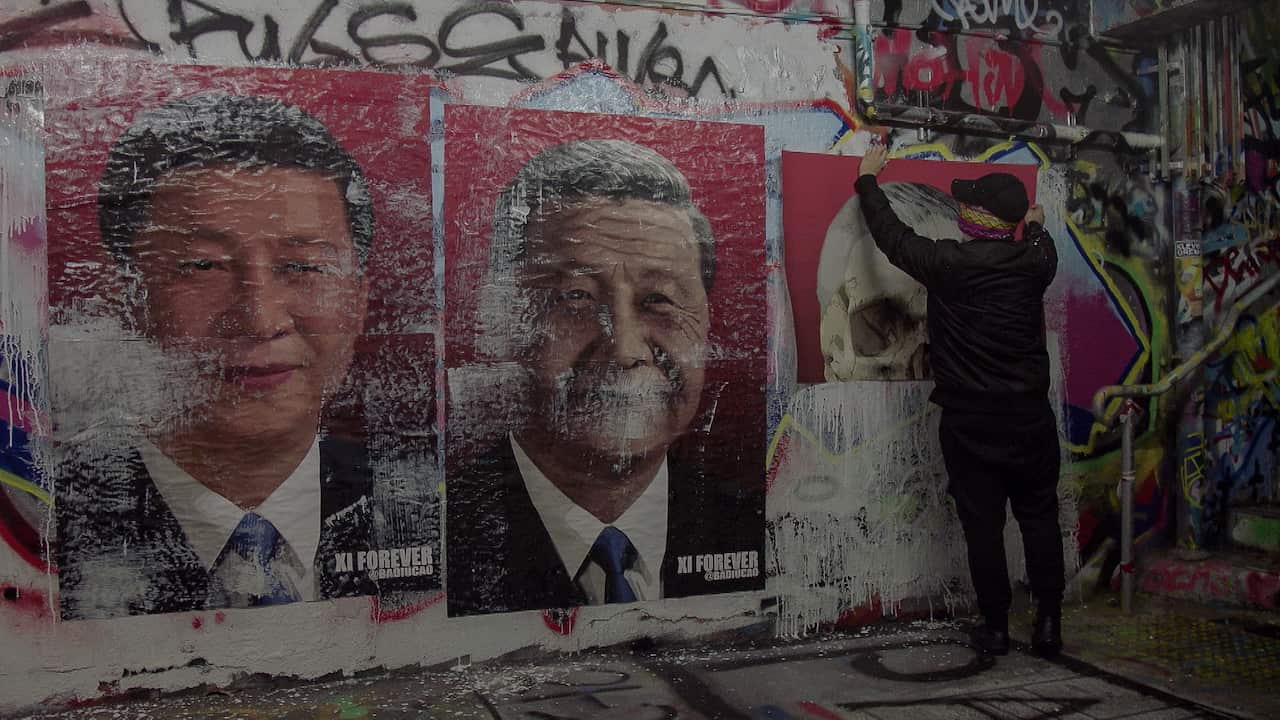 Badiucao pastes up some of his posters at the University of Sydney.