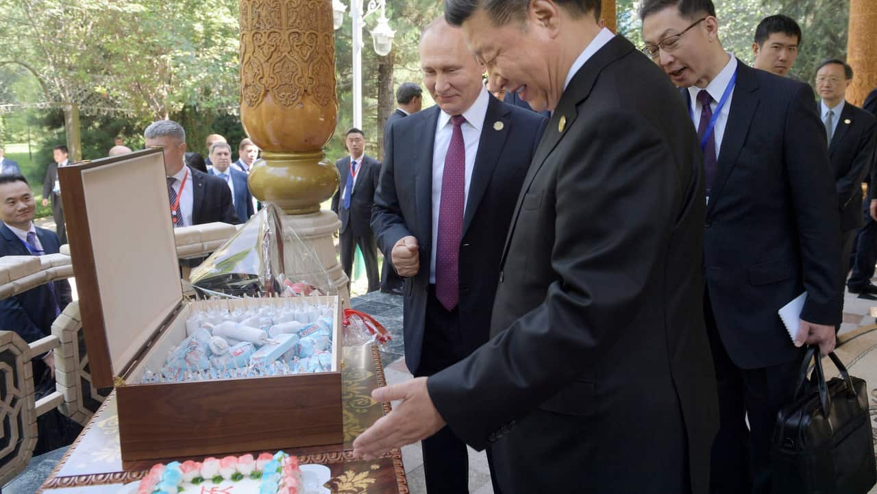 Russian President Vladimir Putin, left, Chinese President Xi Jinping, right, prepare to eat birthday cake.