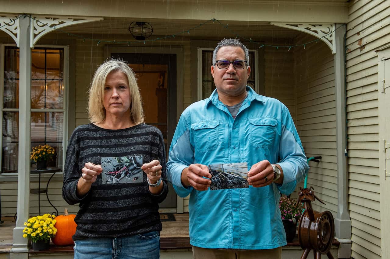 Jennifer and Ryan Cashman hold photos of the burnt remnants of their former home and belongings in Paradise, California.