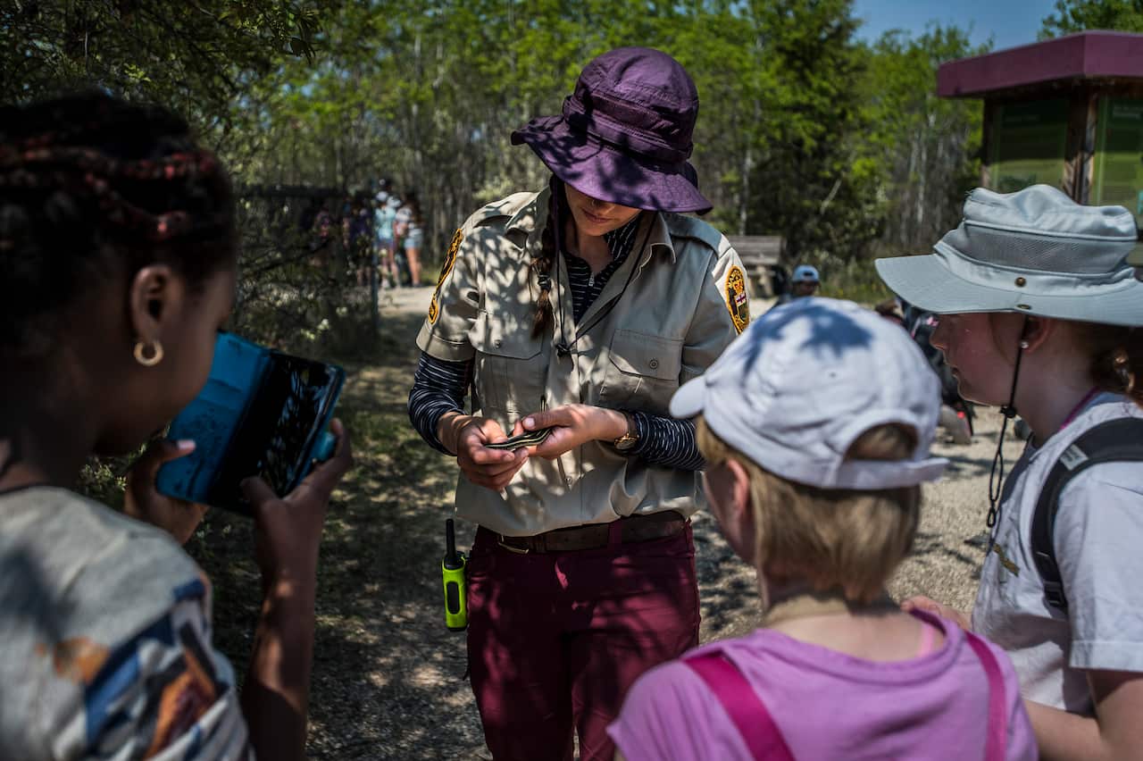 Abby Tye, who works as an interpreter at the Narcisse Snake Dens, shows students how to hold a snake, in Narcisse, Canada.