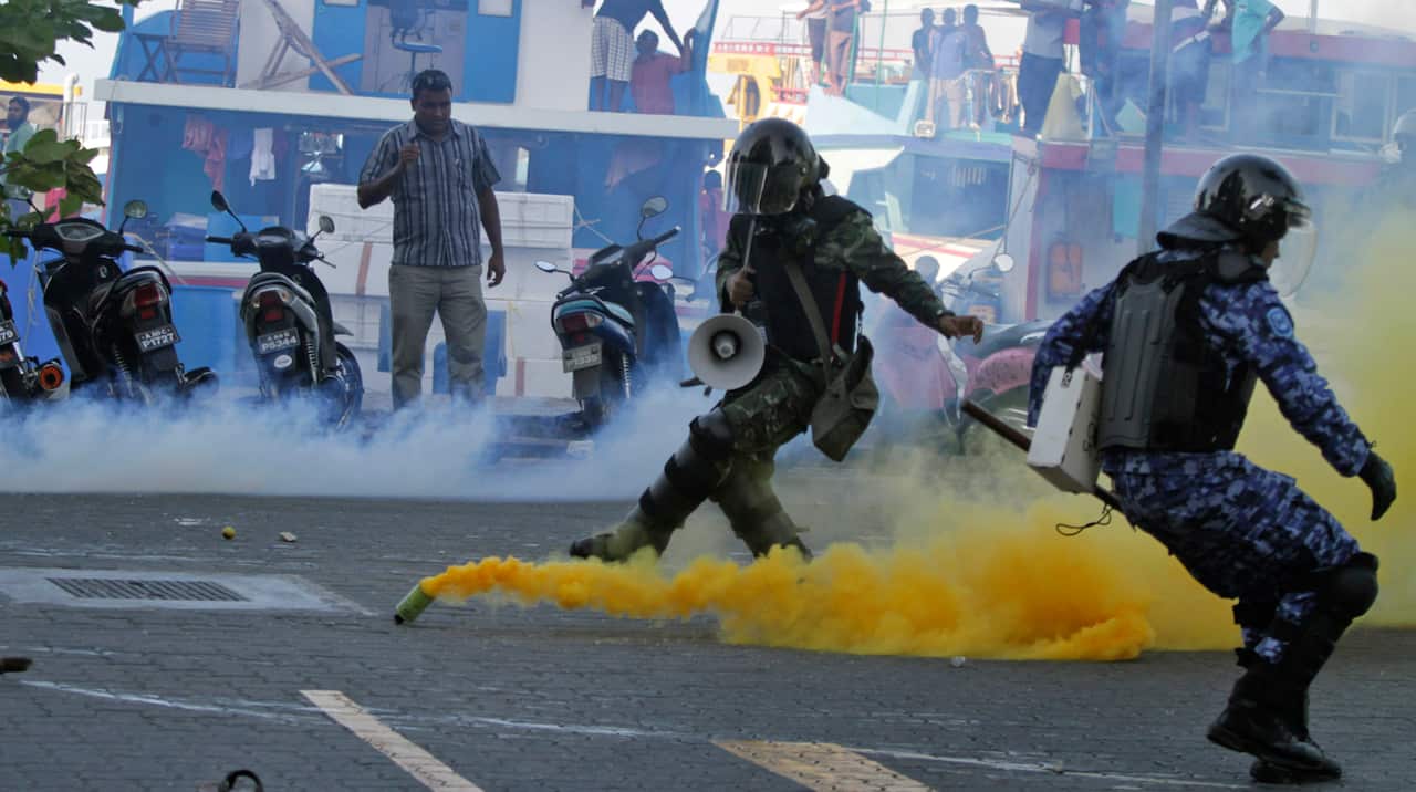 A Maldivian army soldier and policeman take cover as a Nasheed supporter hurls back a tear gas canister thrown during a protest in Male, Maldives, on Feb 8 2012