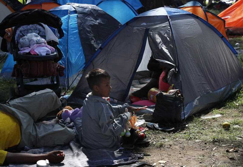 A migrant child sits outside a tent, taking shelter at the Jesus Martinez stadium in Mexico City.