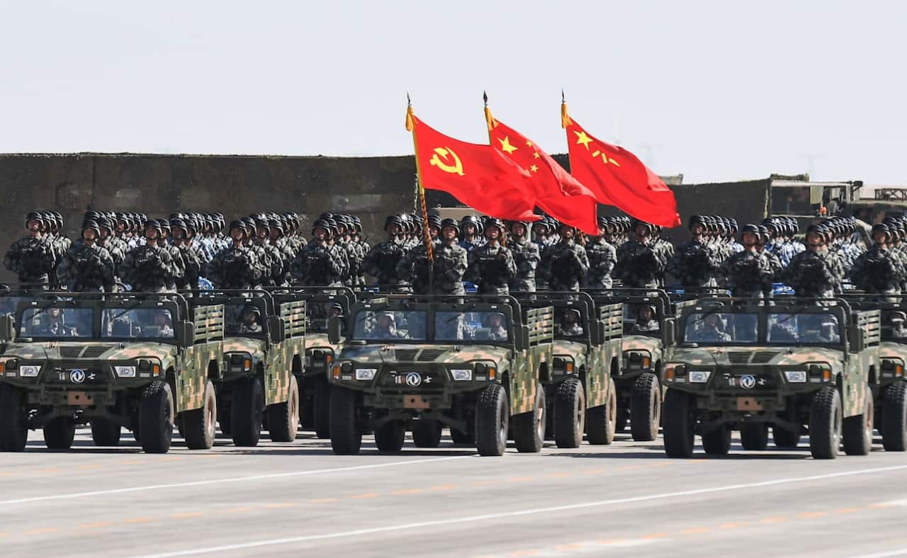Chinese soldiers carry the flags of (L to R) the Communist Party, the state, and the People's Liberation Army during a military parade (Getty)